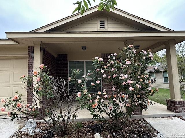 view of home's exterior with a porch, brick siding, and a garage