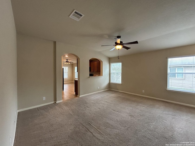spare room with a ceiling fan, visible vents, light colored carpet, and baseboards