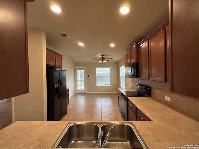 kitchen featuring a sink, decorative backsplash, black appliances, visible vents, and baseboards