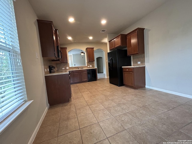 kitchen with black appliances, arched walkways, visible vents, and backsplash