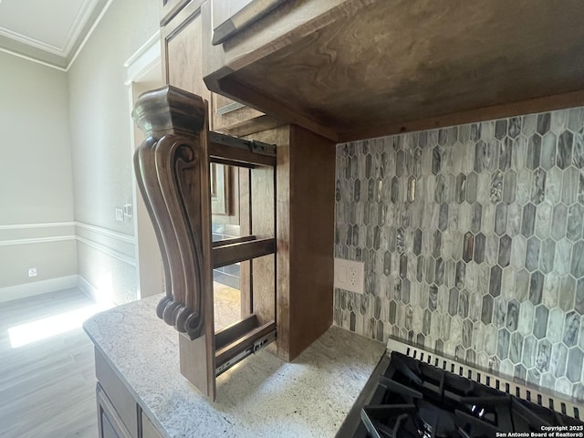 room details with baseboards, wood finished floors, crown molding, and light stone counters