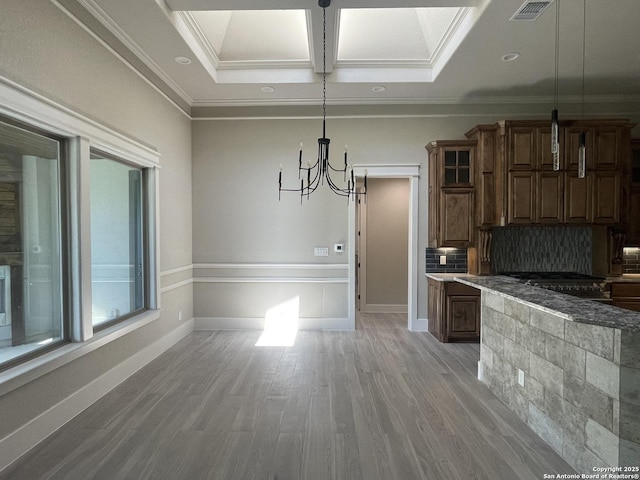 unfurnished dining area with crown molding, visible vents, baseboards, light wood finished floors, and a notable chandelier