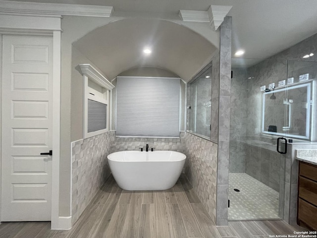 full bath with tile walls, a shower stall, vanity, a freestanding tub, and wood finished floors