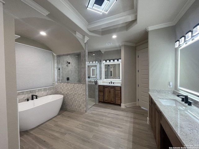bathroom featuring a sink, a freestanding tub, crown molding, a stall shower, and two vanities