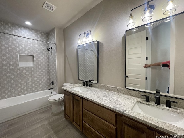 full bath featuring visible vents, toilet, tub / shower combination, and a sink
