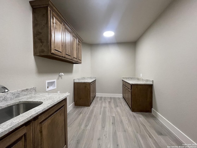 laundry area with a sink, cabinet space, washer hookup, light wood-style flooring, and baseboards