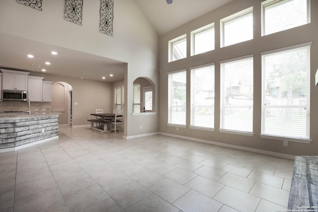 723 Decathlon, San Antonio, TX 78245 - unfurnished living room featuring light tile patterned flooring, a wealth of natural light, and arched walkways