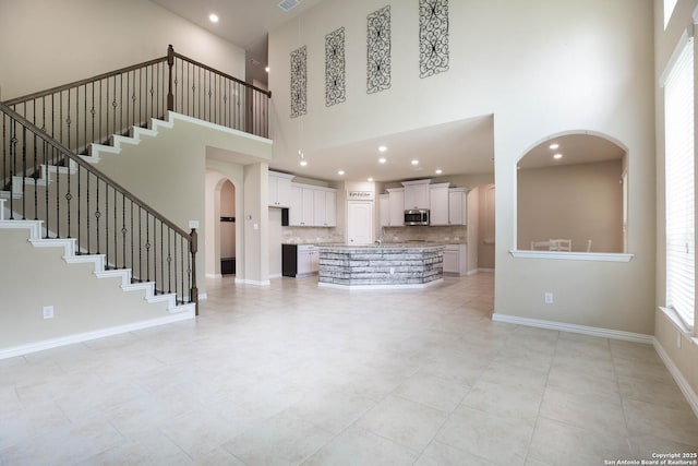 723 Decathlon, San Antonio, TX 78245 - unfurnished living room featuring stairway, light tile patterned floors, arched walkways, and a high ceiling