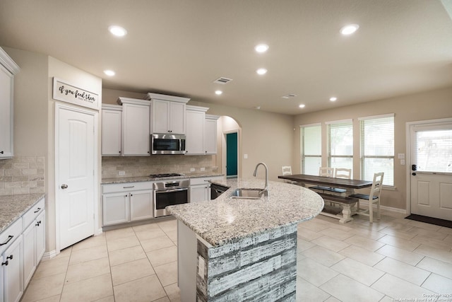 723 Decathlon, San Antonio, TX 78245 - kitchen with decorative backsplash, a sink, appliances with stainless steel finishes, arched walkways, and an island with sink