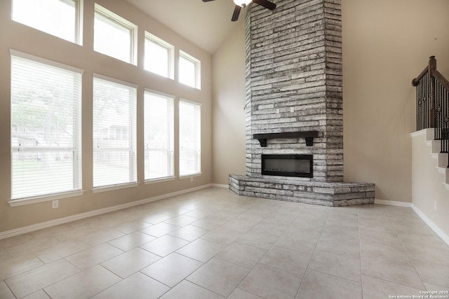 723 Decathlon, San Antonio, TX 78245 - unfurnished living room featuring ceiling fan, baseboards, tile patterned floors, a towering ceiling, and a stone fireplace