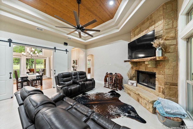 living area with a barn door, a raised ceiling, visible vents, wood ceiling, and arched walkways