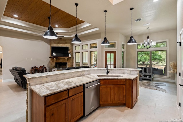 kitchen featuring a sink, a raised ceiling, open floor plan, dishwasher, and brown cabinetry