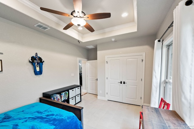 bedroom with a raised ceiling, visible vents, a ceiling fan, and ornamental molding