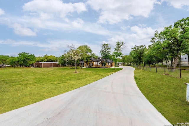 view of home's community with fence, driveway, and a lawn