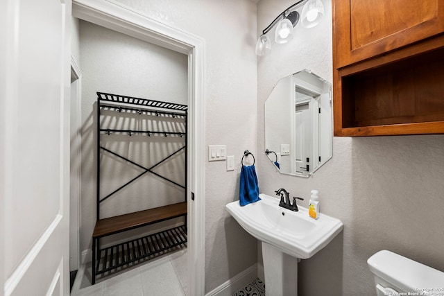 bathroom featuring tile patterned floors, baseboards, toilet, and a sink