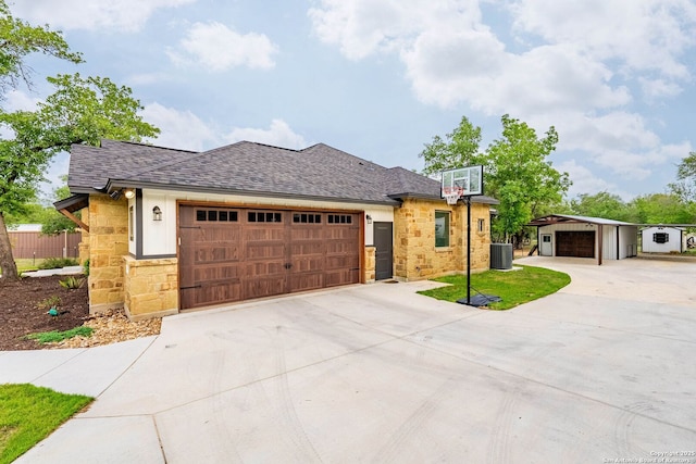 ranch-style home with a shingled roof, central air condition unit, driveway, and stone siding