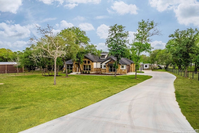 view of front of home featuring fence, driveway, a front lawn, and stone siding