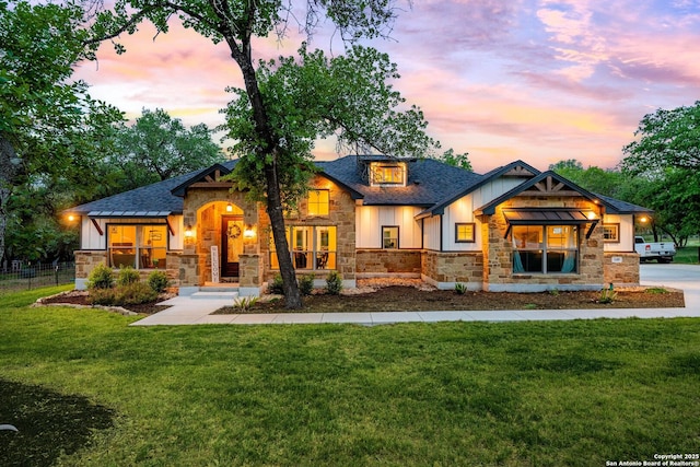 view of front of home featuring a shingled roof, fence, a front lawn, and stone siding