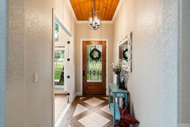 interior space with ornamental molding, an inviting chandelier, and a textured wall
