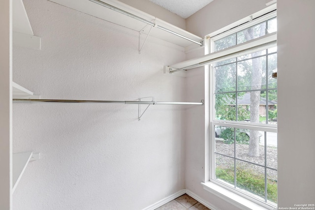 walk in closet with light tile patterned floors