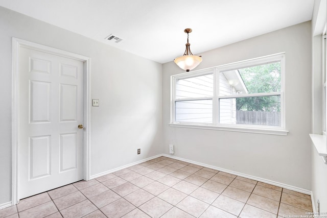 spare room featuring light tile patterned flooring, visible vents, and baseboards