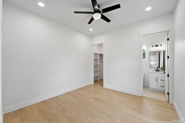 265 Vaquero Dr, Pipe Creek, TX 78063 - unfurnished bedroom with light wood-style flooring, baseboards, recessed lighting, a walk in closet, and a sink
