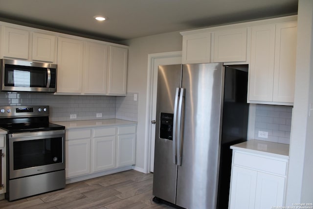 kitchen featuring stainless steel appliances, light countertops, light wood-style flooring, and white cabinets
