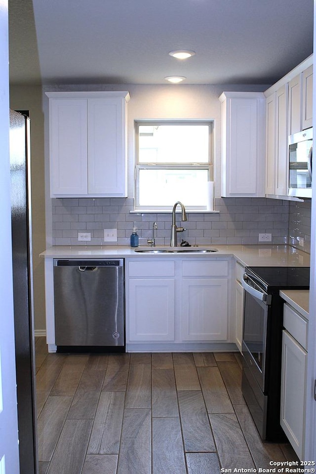 kitchen featuring a sink, backsplash, stainless steel appliances, and white cabinetry