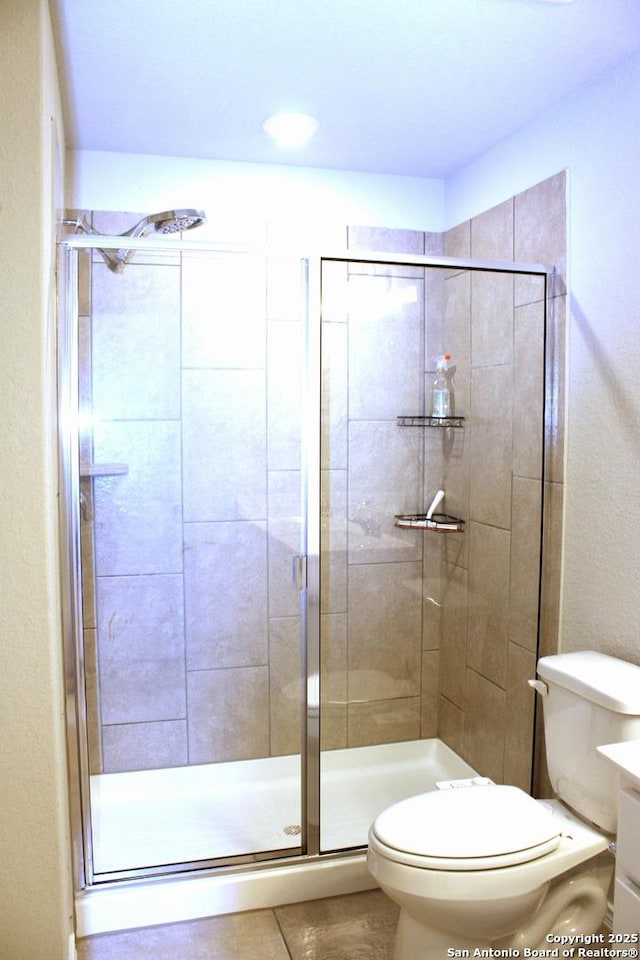 full bathroom featuring tile patterned floors, toilet, and a stall shower