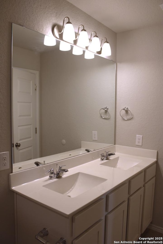 bathroom with double vanity, a sink, and a textured wall