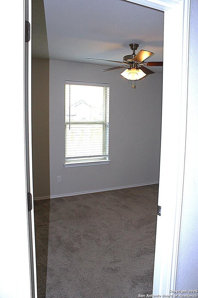 unfurnished room featuring a ceiling fan, carpet floors, and baseboards