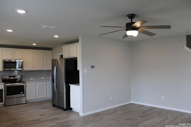 kitchen with white cabinets, appliances with stainless steel finishes, ceiling fan, light wood-style floors, and light countertops