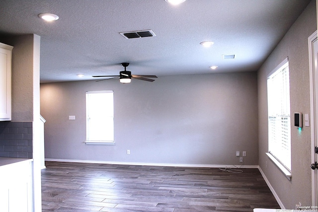 unfurnished living room featuring wood finished floors, ceiling fan, visible vents, and baseboards