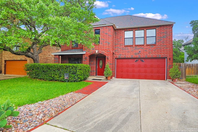 traditional home with a front yard, driveway, brick siding, an attached garage, and fence