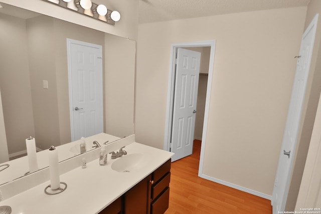 bathroom featuring wood finished floors, vanity, and baseboards