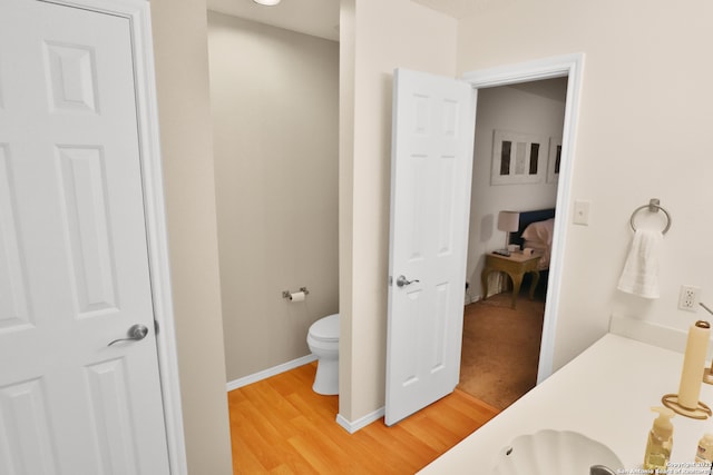 bathroom featuring toilet, wood finished floors, and baseboards