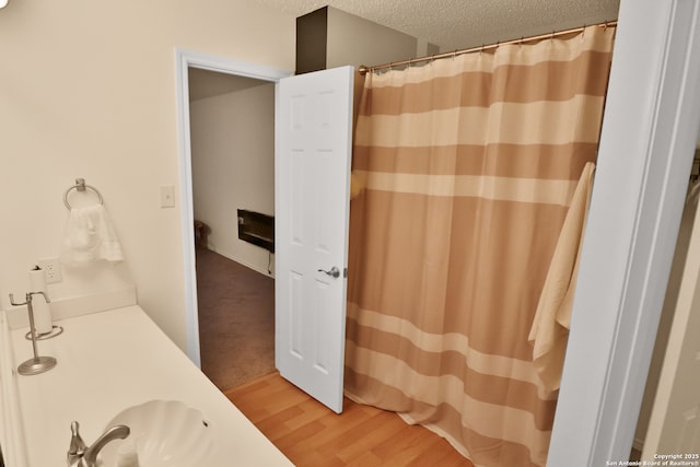 full bath featuring wood finished floors, a textured ceiling, and a shower with shower curtain