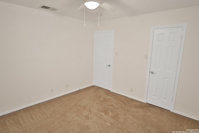 carpeted spare room with baseboards, visible vents, and ceiling fan