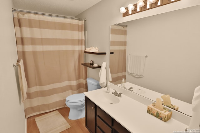 bathroom with a textured ceiling, curtained shower, toilet, wood finished floors, and vanity