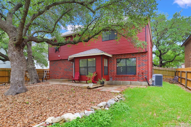 view of front facade with a fenced backyard, a patio, roof with shingles, cooling unit, and a front yard