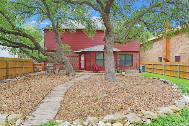 rear view of property with cooling unit, a patio area, brick siding, and a fenced backyard