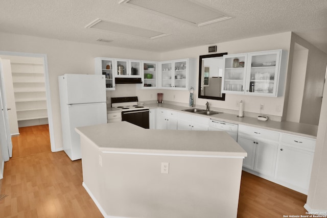 kitchen featuring a sink, a kitchen island, light wood-style flooring, white appliances, and white cabinets