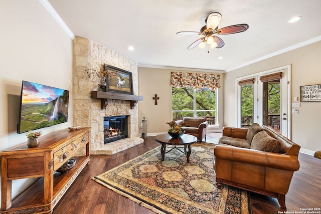 living area featuring a ceiling fan, a fireplace, dark wood-style flooring, and crown molding