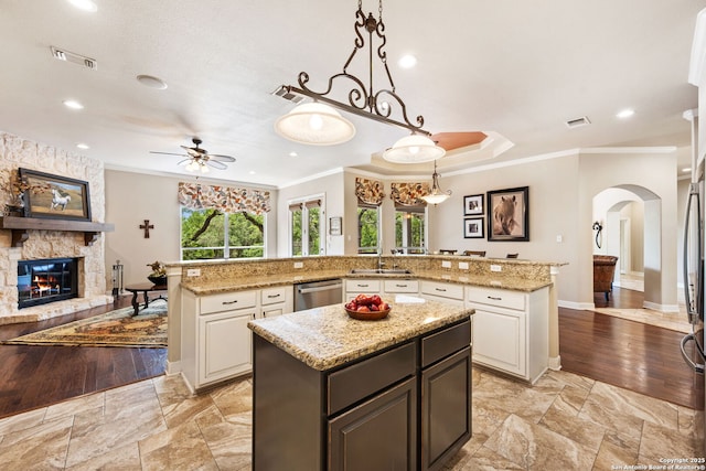 kitchen with stainless steel dishwasher, arched walkways, a large island, ornamental molding, and a ceiling fan