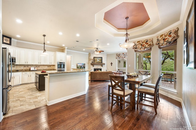 dining room featuring recessed lighting, hardwood / wood-style flooring, a large fireplace, ceiling fan, and crown molding
