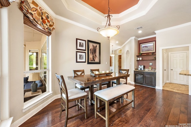 dining room featuring dark wood-style floors, visible vents, baseboards, ornamental molding, and arched walkways