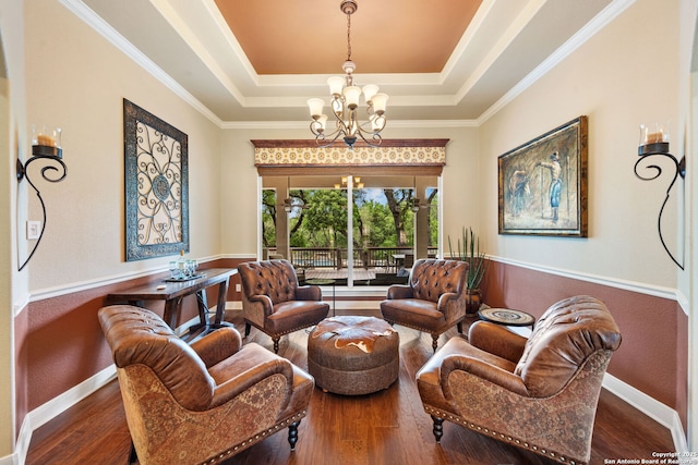 sitting room with a chandelier, baseboards, a raised ceiling, and wood finished floors
