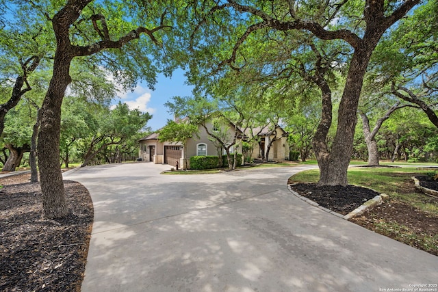 view of front facade with stucco siding, a garage, and curved driveway