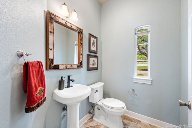 half bathroom with toilet and baseboards