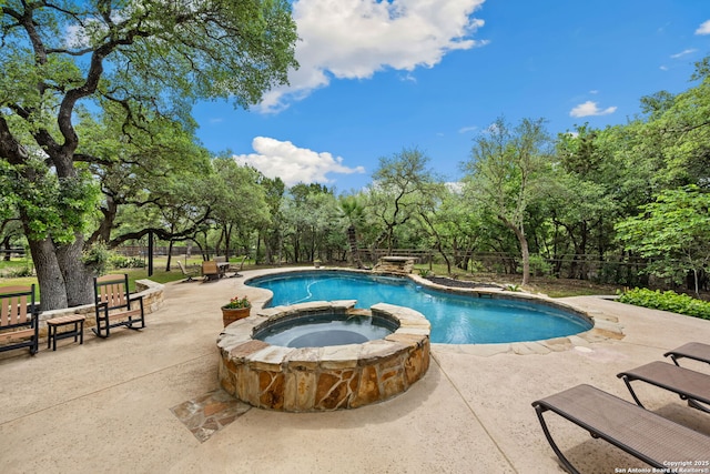 view of swimming pool featuring fence, a pool with connected hot tub, and a patio area